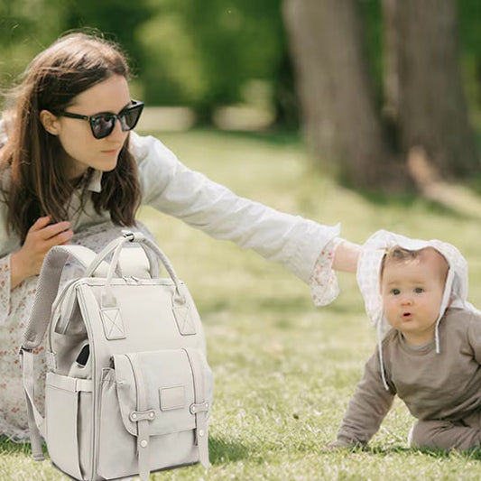 une mère avec bébé et son sac à dos à-langer au parc